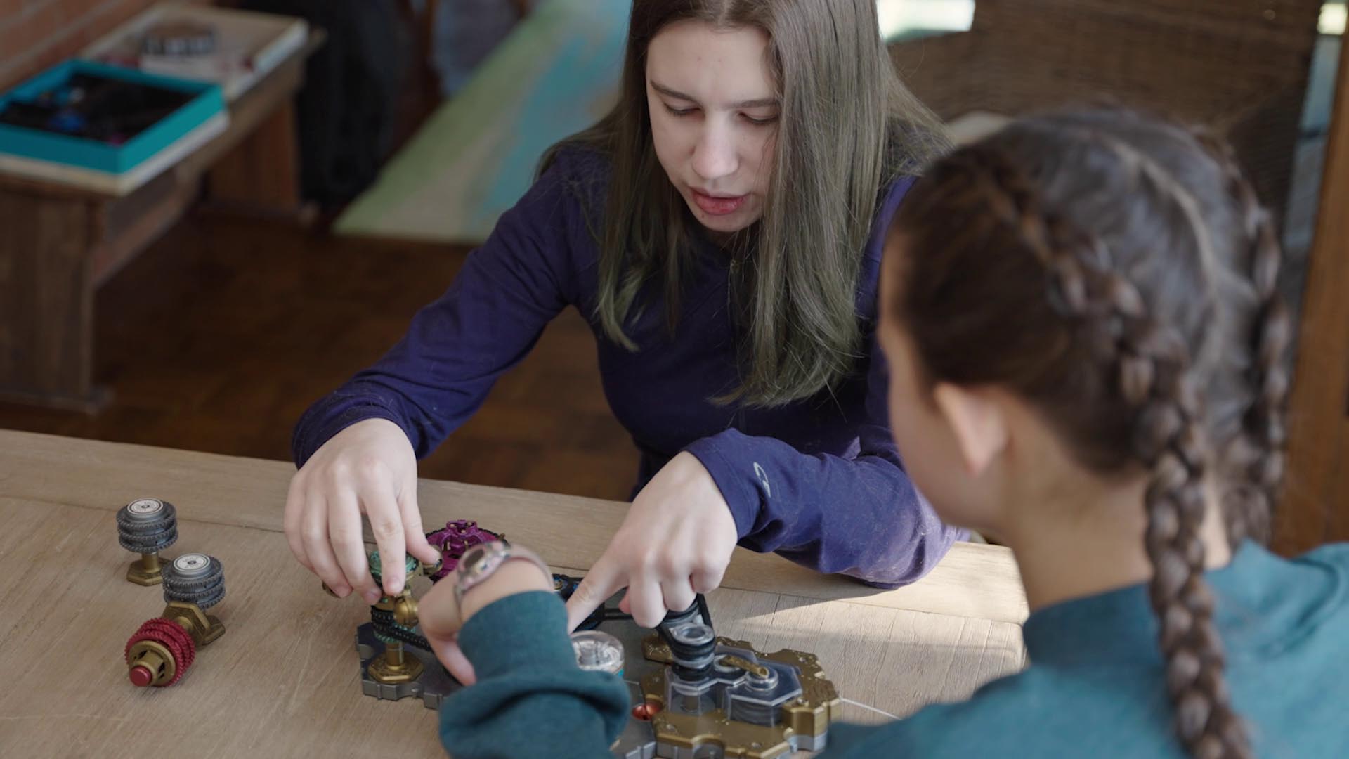 Girl playing with Spintronics, pointing to a part and explaining what's happening.