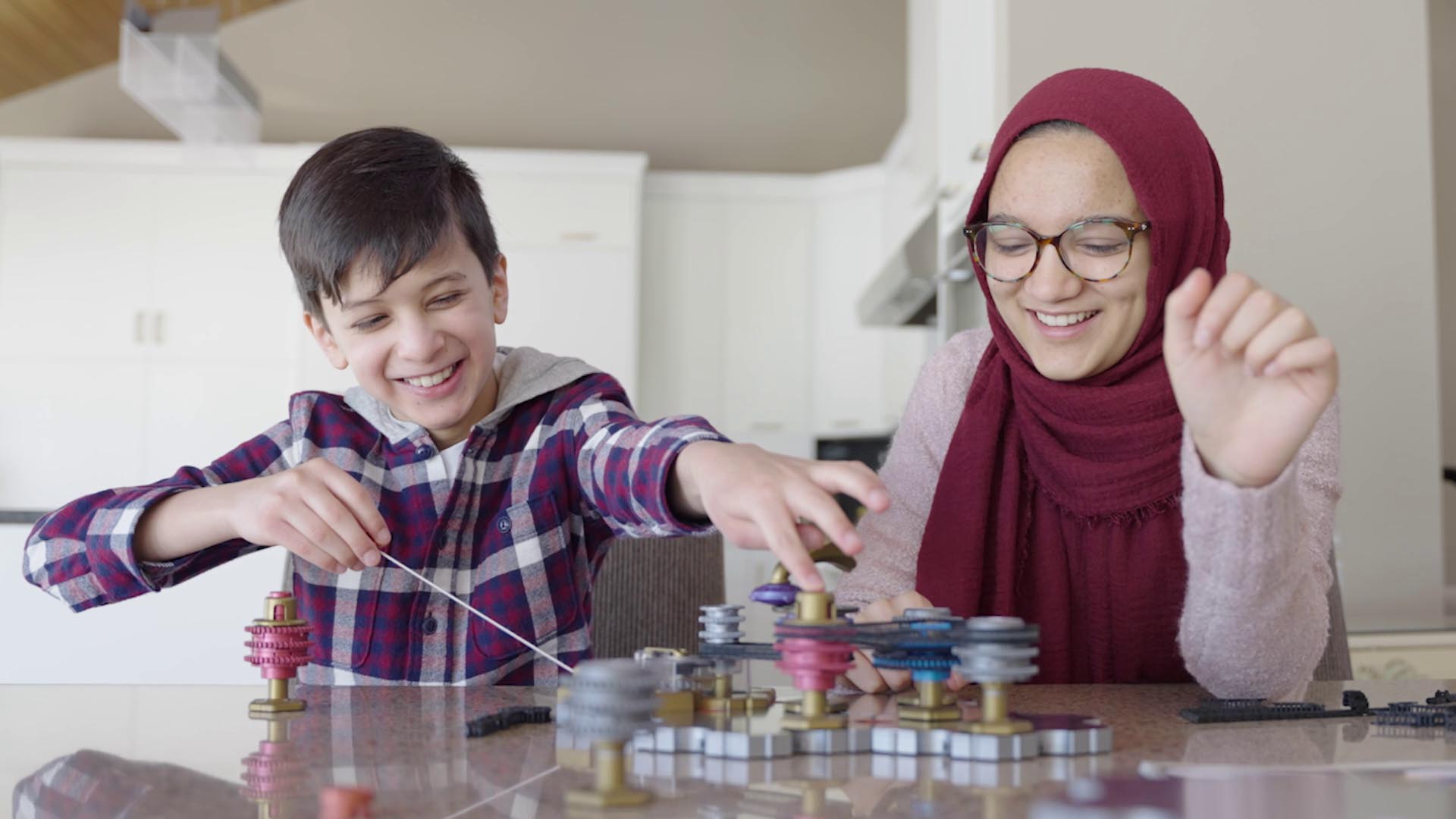 Boy and girl playing with Spintronics, pulling the string back.